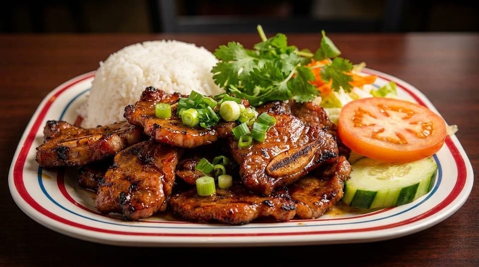 Grilled pork ribs with rice, garnished with green onions, cilantro, tomato, and cucumber.